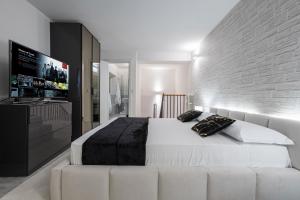 a bedroom with a white bed and a flat screen tv at Gramsci Prestige Apartment in Bologna