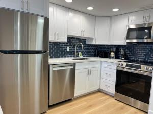 Una cocina con gabinetes blancos y un refrigerador de acero inoxidable. en Ilikai Tower 1936 condo, en Honolulu