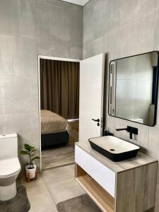 une salle de bain avec un lavabo et des toilettes et un lit dans l'établissement Wabi Sabi, à Johannesbourg
