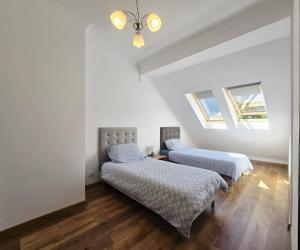 2 Betten in einem Zimmer mit weißen Wänden und Holzböden in der Unterkunft Dom z jacuzzi, house with a hot tub in Gardna Wielka