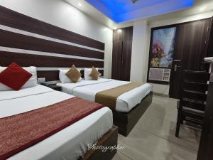 a hotel room with two beds and a television at Hotel Blu Bird in New Delhi +4 photos