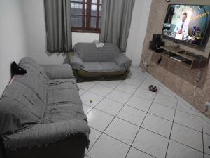 ein Wohnzimmer mit Sofa und Fernseher in der Unterkunft Casa Tupy próxima a praia e restaurantes in Praia Grande