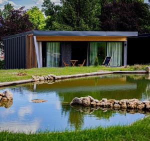 ein Haus mit einem Teich davor in der Unterkunft Lodges d'Exception avec jacuzzi privé I Montluçon I Auvergne in Prémilhat