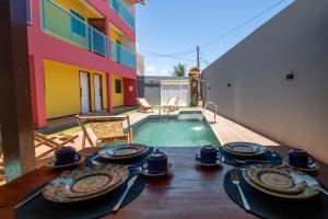 a table with plates of food on top of it next to a pool at Zen Spa Houses in São Miguel dos Milagres