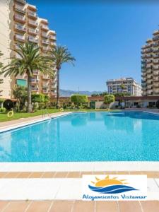 ein großer Swimmingpool mit Palmen und Gebäuden in der Unterkunft Apartamento Las Góndolas Playa ALOJAMIENTOS VISTAMAR in Almuñécar