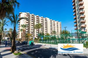 ein großes Apartmenthaus in einer Straße mit Palmen in der Unterkunft Apartamento Las Góndolas Playa ALOJAMIENTOS VISTAMAR in Almuñécar