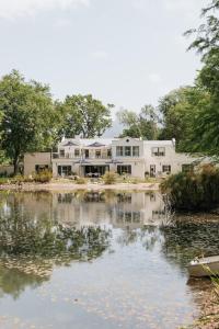una gran casa blanca junto a un cuerpo de agua en Klein Champagne Guesthouse and Cottages, en Franschhoek