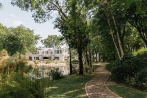 una casa blanca con estanque y árboles en Klein Champagne Guesthouse and Cottages, en Franschhoek