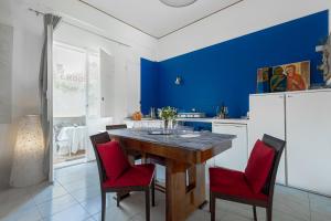 a kitchen with a wooden table and red chairs at ArtRoom Garden in Noto