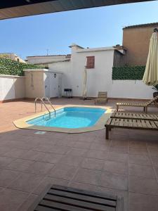 einen Pool mit einer Bank und einem Sonnenschirm in der Unterkunft Alojamientos El Carmen in Ugíjar