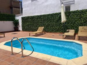 a swimming pool with two chairs and an umbrella at El Carmen - Villa Rural con Piscina Privada y Patio Andaluz in Ugíjar