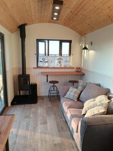 ein Wohnzimmer mit einem Sofa und einem Holzofen in der Unterkunft Bramley Shepherds Hut - Whimple in Whimple