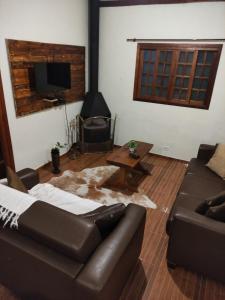 een woonkamer met een leren bank en een tafel bij Refúgio com Hidro, Lareira, Café da Manhã e Vista da Natureza in Santo Antônio do Pinhal