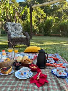 een picknicktafel met eten en koffie op een kleed bij Refúgio com Hidro, Lareira, Café da Manhã e Vista da Natureza in Santo Antônio do Pinhal