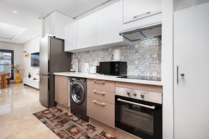 eine Küche mit weißen Schränken und einer Waschmaschine und einem Trockner in der Unterkunft Modern Comfortable Apartment - Corniche Hassan II in Casablanca + 10 Fotos