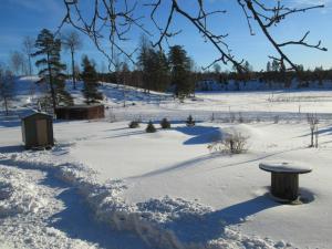 a snow covered field with a bench in the snow at Stuga med bastu i naturen nära Stockholm in Järna +13 photos