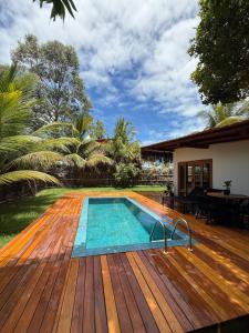 una terrazza in legno con piscina e una casa di Corumbau Bangalôs a Corumbau
