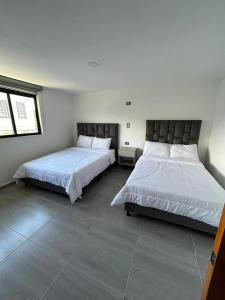 two beds in a room with white walls at Yellow House in Manizales
