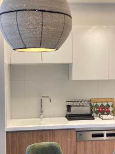 une cuisine avec une lampe suspendue au plafond dans l'établissement Aurelia Residence, à Ampavris