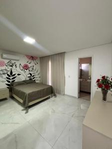 ein Schlafzimmer mit einem Bett und Blumen an der Wand in der Unterkunft Casa Moderna & Conforto in Eusébio