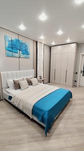 ein Schlafzimmer mit einem großen Bett mit einer blauen Decke in der Unterkunft ЖК "Nomad" 2-комнатный ЛЮКС в центре города in Almaty
