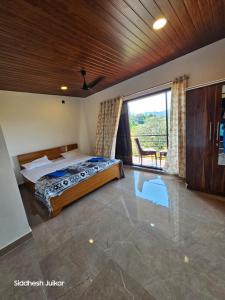 ein Schlafzimmer mit einem Bett und einem großen Fenster in der Unterkunft Anugraha Homestay in Alībāg