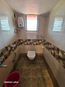 ein kleines Badezimmer mit Toilette und Fenster in der Unterkunft Anugraha Homestay in Alībāg