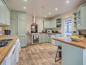 Duddonにある3 Bed in The Green 88586のキッチン(緑のキャビネット付)、カウンターにフルーツを用意しています。