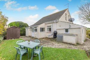 ein Haus mit einem Tisch und Stühlen im Hof in der Unterkunft Cornerways in Worth Matravers