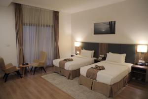 a hotel room with two beds and a tv on the wall at Hotel Boutique Elmos - Meskel Flower in Addis Ababa