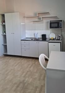 a kitchen with white cabinets and a counter top at Suíte Harmonia 1 in Campo Grande