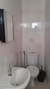 a white bathroom with a toilet and a sink at Suíte Harmonia 1 in Campo Grande