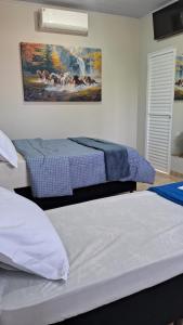 a bedroom with two beds and a painting on the wall at Suíte Harmonia 1 in Campo Grande