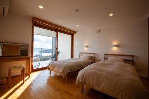 two beds in a room with a large window at USHIMADO Villa - Vacation STAY 61741v in Setouchi