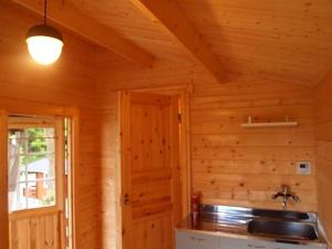 une cuisine dans une cabane en rondins avec un évier dans l'établissement Foresters Village Kobitto Southern Alps Camp Field - Vacation STAY 78097v, à Shirasu