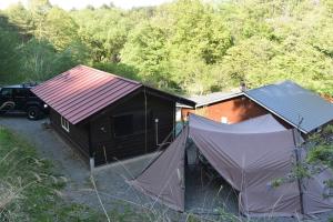 une cabane au toit rouge et deux tentes dans l'établissement Foresters Village Kobitto Southern Alps Camp Field - Vacation STAY 78099v, à Shirasu