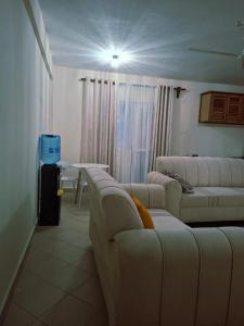 a living room with white couches and a table at Evara Luxe stay in Mombasa +5 photos
