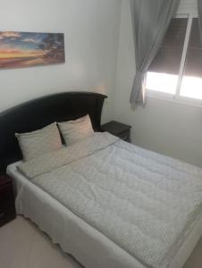 ein Bett in einem weißen Zimmer mit einem Fenster in der Unterkunft MARIA HOUSE in Imsouane