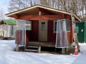 a small red cabin with a porch in the snow at Kitakaruizawa Acorn Mountain Ichibanboshi Campsite - Vacation STAY 53268v in Kita-karuizawa