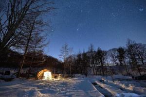 a lit up tent in a snowy field at night at Kitakaruizawa Acorn Mountain Ichibanboshi Campsite - Vacation STAY 53268v in Kita-karuizawa +6 photos