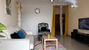 a living room with a white couch and a chair at BARAN Home in Yaoundé
