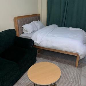 une chambre avec un lit, une chaise et une table dans l'établissement Lawrence place, à Nairobi