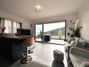 a living room with a couch and a desk with a large window at Modern Luxury - Sea View over Èze Village in Èze