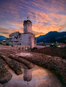 a castle with a reflection in a body of water at Casa Rosmini rooms, Dolomia best home in Trento