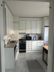 a kitchen with white cabinets and a sink and a stove at Hostel400Kokkola Kaksio Hollihaka in Kokkola
