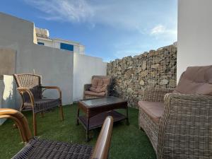 un patio con sillas, un sofá y una pared en Onar Exclusive Studio Suite, en Oroklini