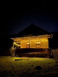 ein Holzhaus mit Lichtern in der Nacht in der Unterkunft Glamping - Casuta de pe Fiad in Romuli