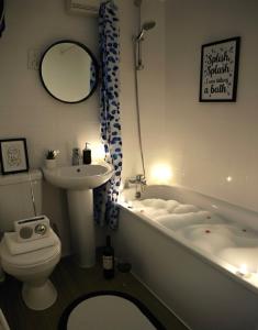a bathroom with a tub and a toilet and a sink at Clifftop Chalet With Pool in Deal