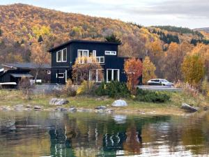 a black house next to a body of water at Sand Beachhouse in Sand