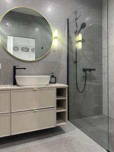 une salle de bain avec un lavabo et une douche avec un miroir dans l'établissement Let's Sea SPA - Premium Apartamenty z ogródkiem, przyjazne zwierzętom, à Gąski